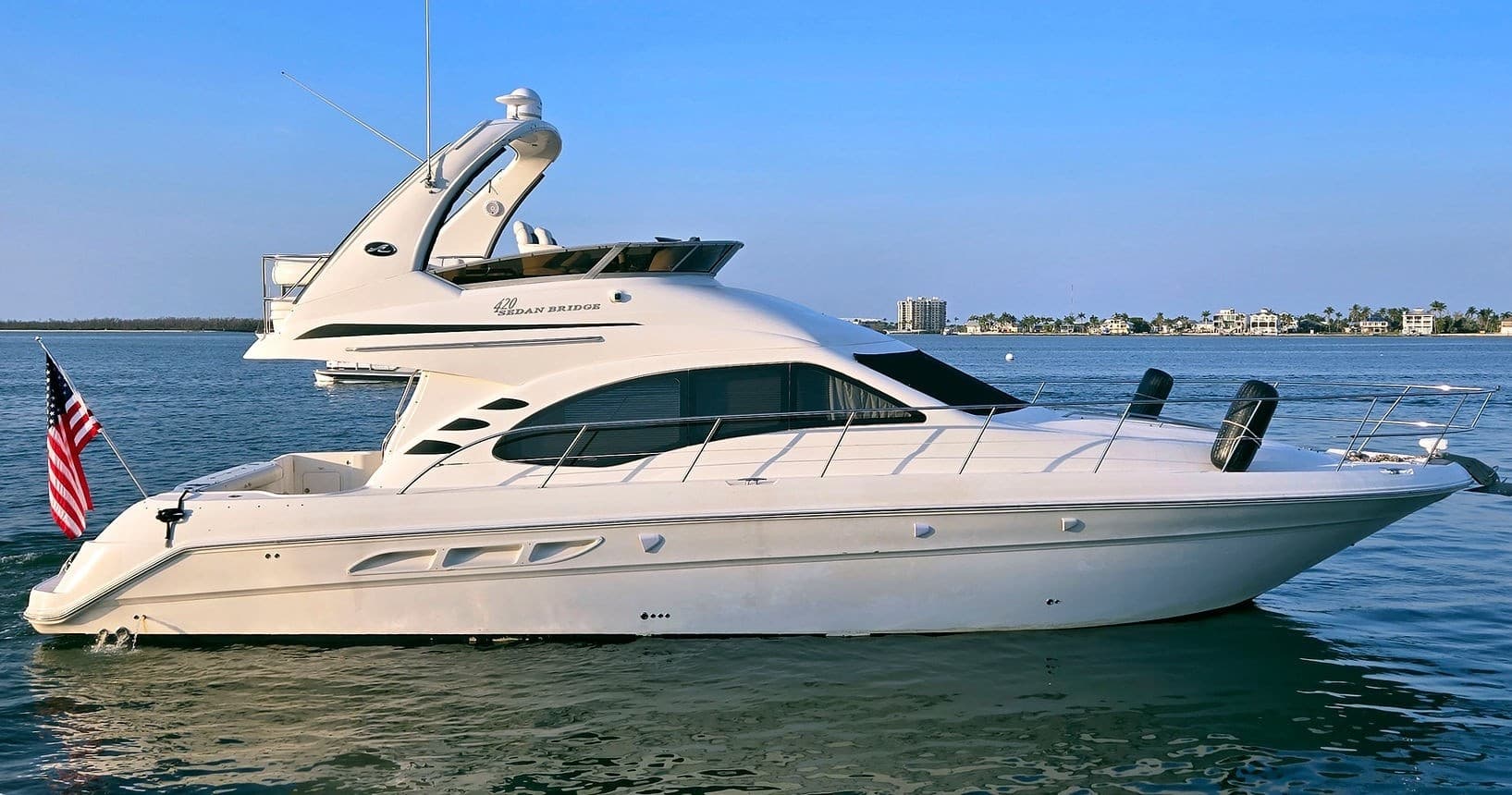 Luxury yacht side profile cruising calm bay under blue sky