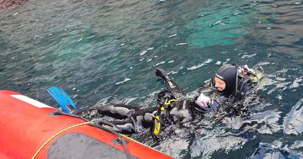 Scuba diver surfacing beside inflatable boat during dive trip