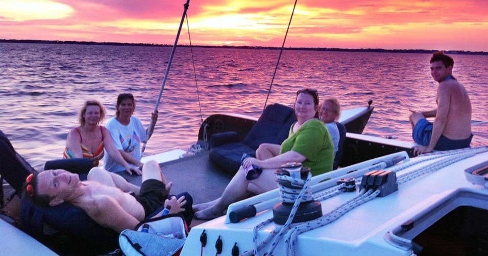 Friends relaxing on catamaran at vibrant sunset on ocean