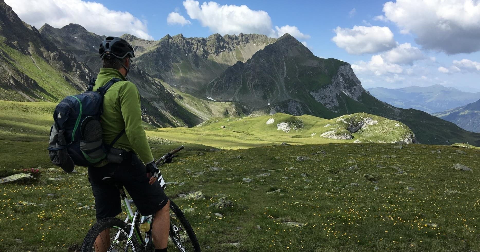 Cyclist overlooking alpine mountain valley on scenic trail