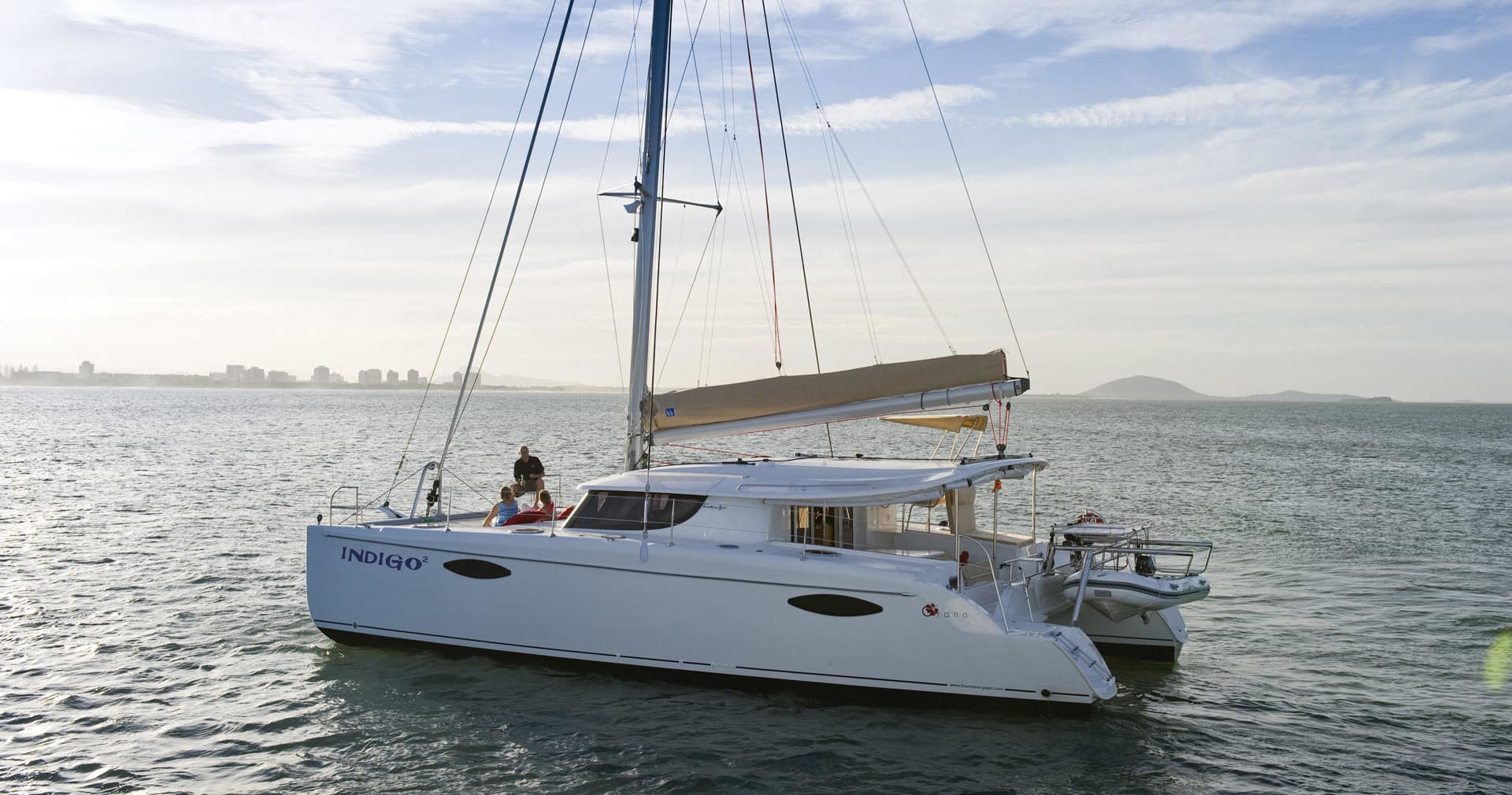 Charter catamaran moored offshore near coastal skyline