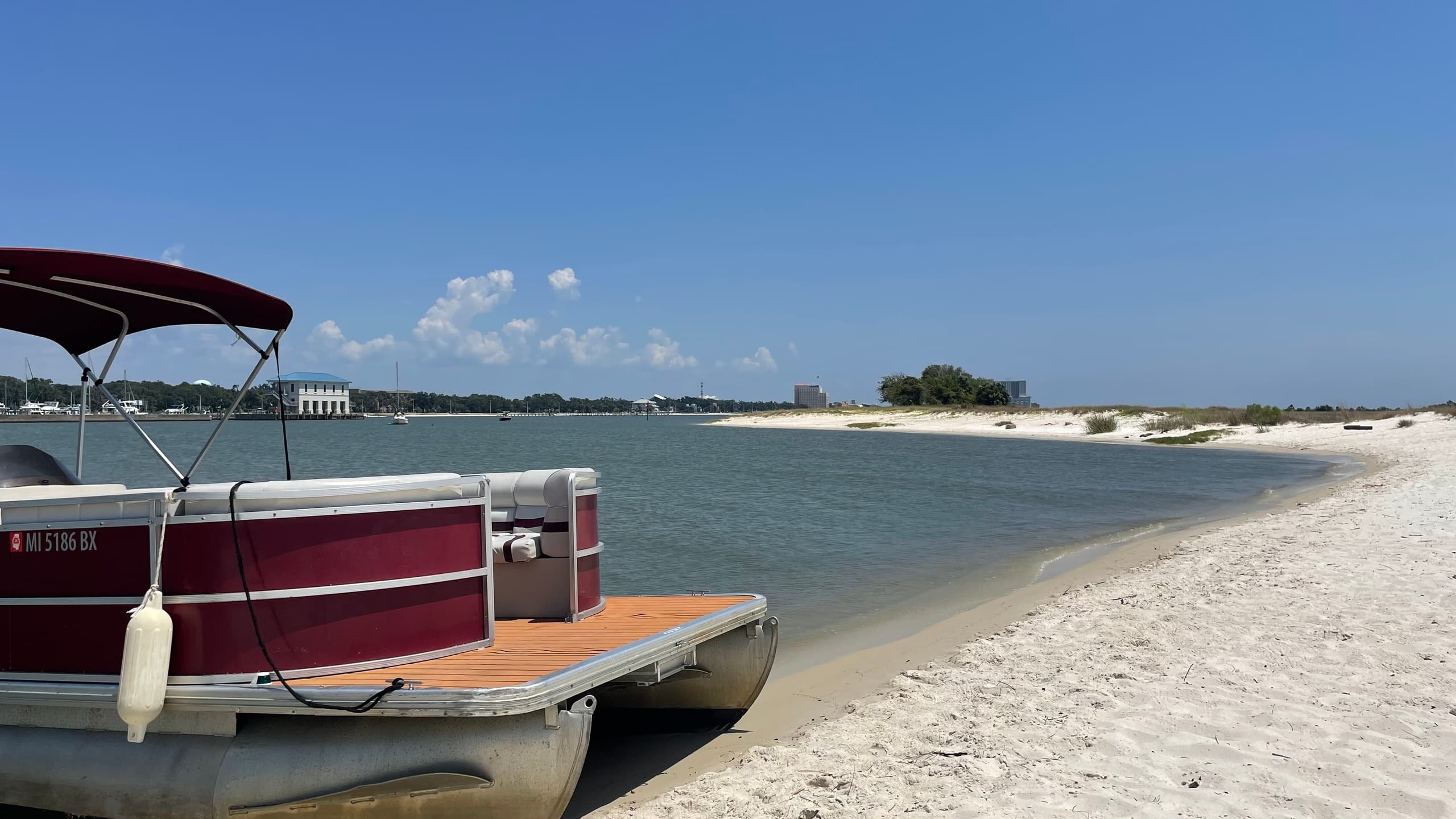 Pontoon moored on sandy beach with calm bay and blue sky