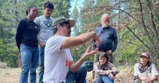 Field instructor pointing during forest mushroom foraging class