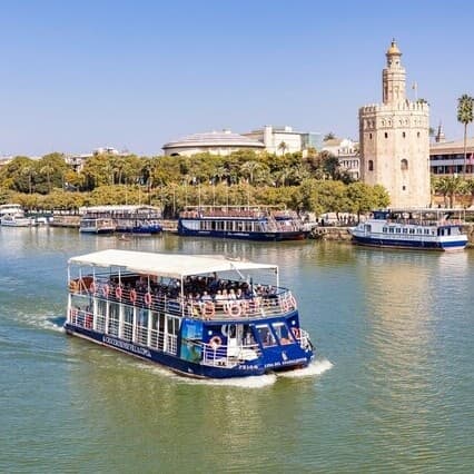 Sightseeing boat cruising Guadalquivir River past Torre del Oro