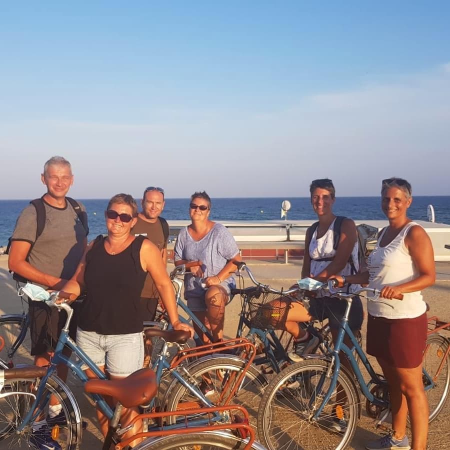 Group of cyclists posing on beachfront promenade at golden hour