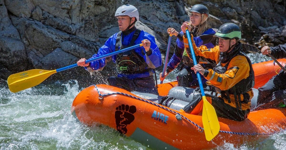 Guides steering inflatable raft through pounding whitewater waves