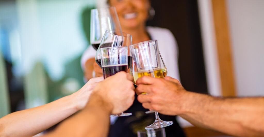 Guests toasting wine glasses during casual Hawaiian cooking class celebration