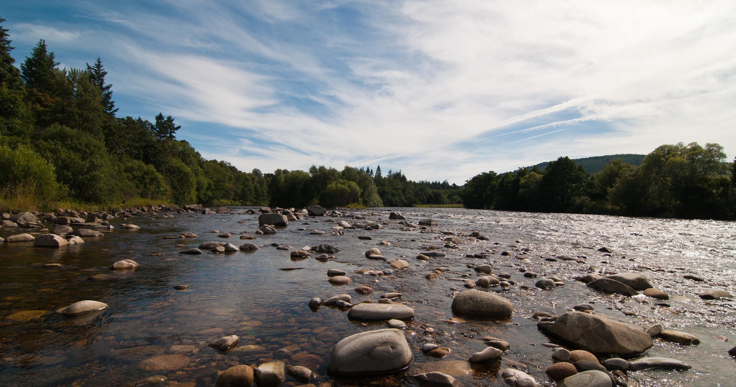 Rocky riverbed with shallow stream and scenic wilderness vista