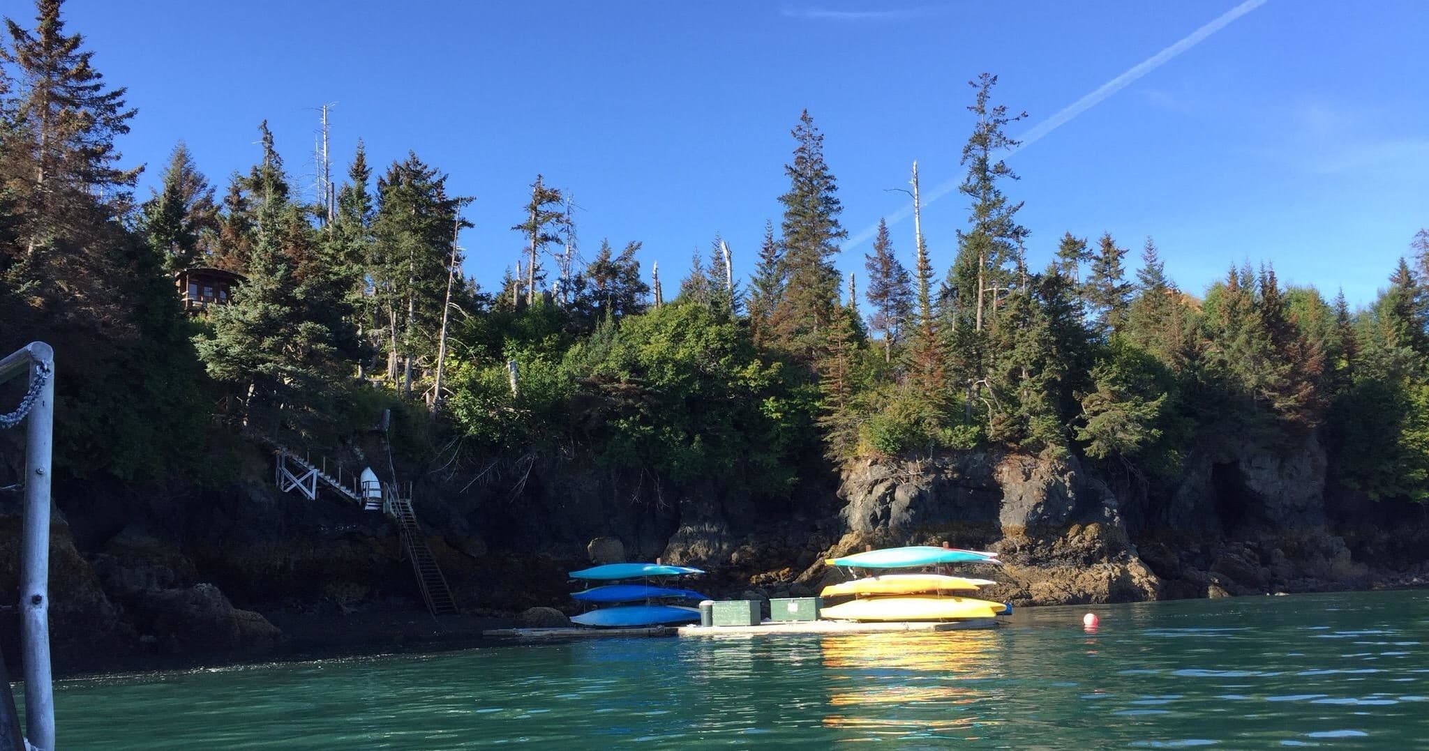 Stacked kayaks and calm inlet near forested island shoreline