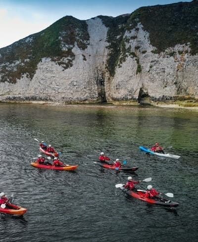 Guided kayak group exploring coastal chalk cliffs and coves