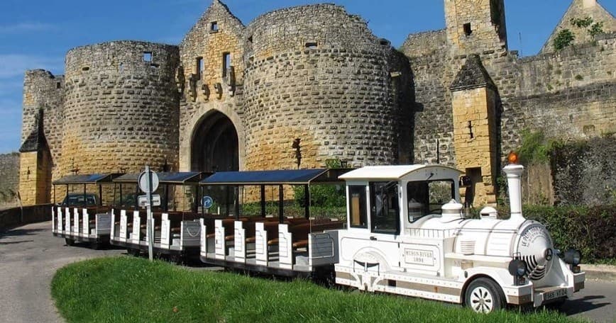 Tourist road train passing medieval Domme fortress in Perigord