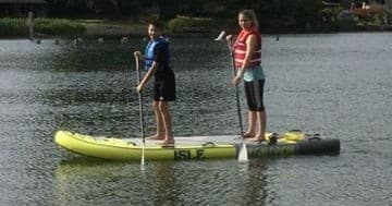 Two stand-up paddleboarders standing on inflatable lake platform