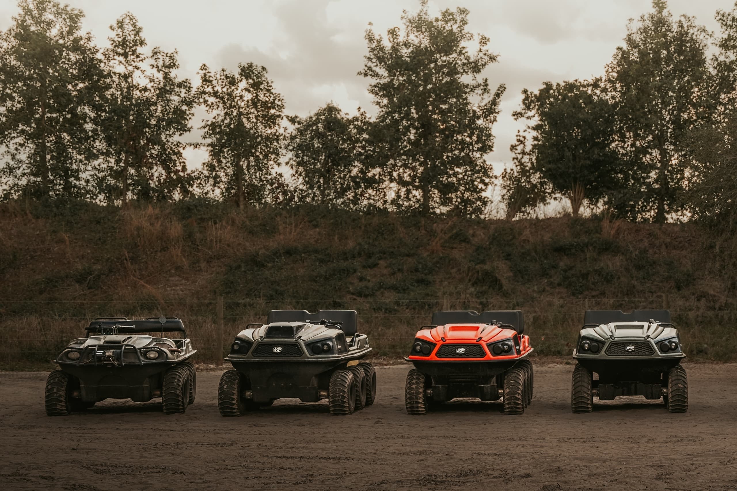 Line of off-road UTVs parked on dirt trail under overcast sky