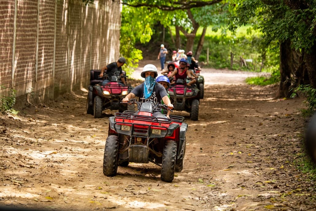 All-terrain vehicle tour on dirt path through shaded jungle road