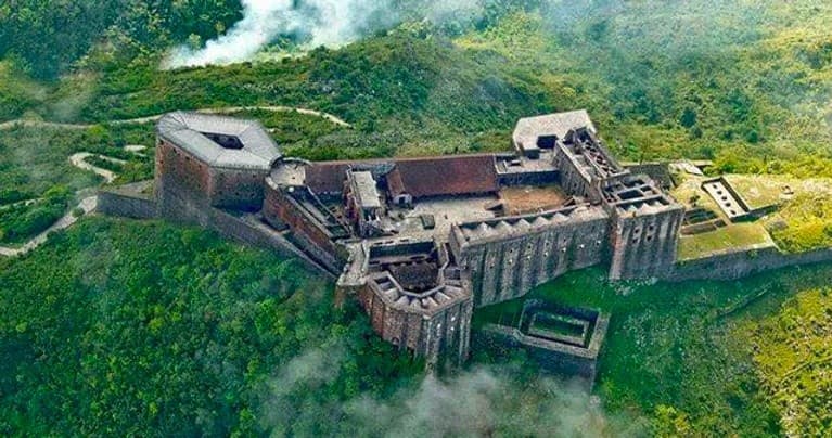 Aerial view of historic coastal fortress and green mountains