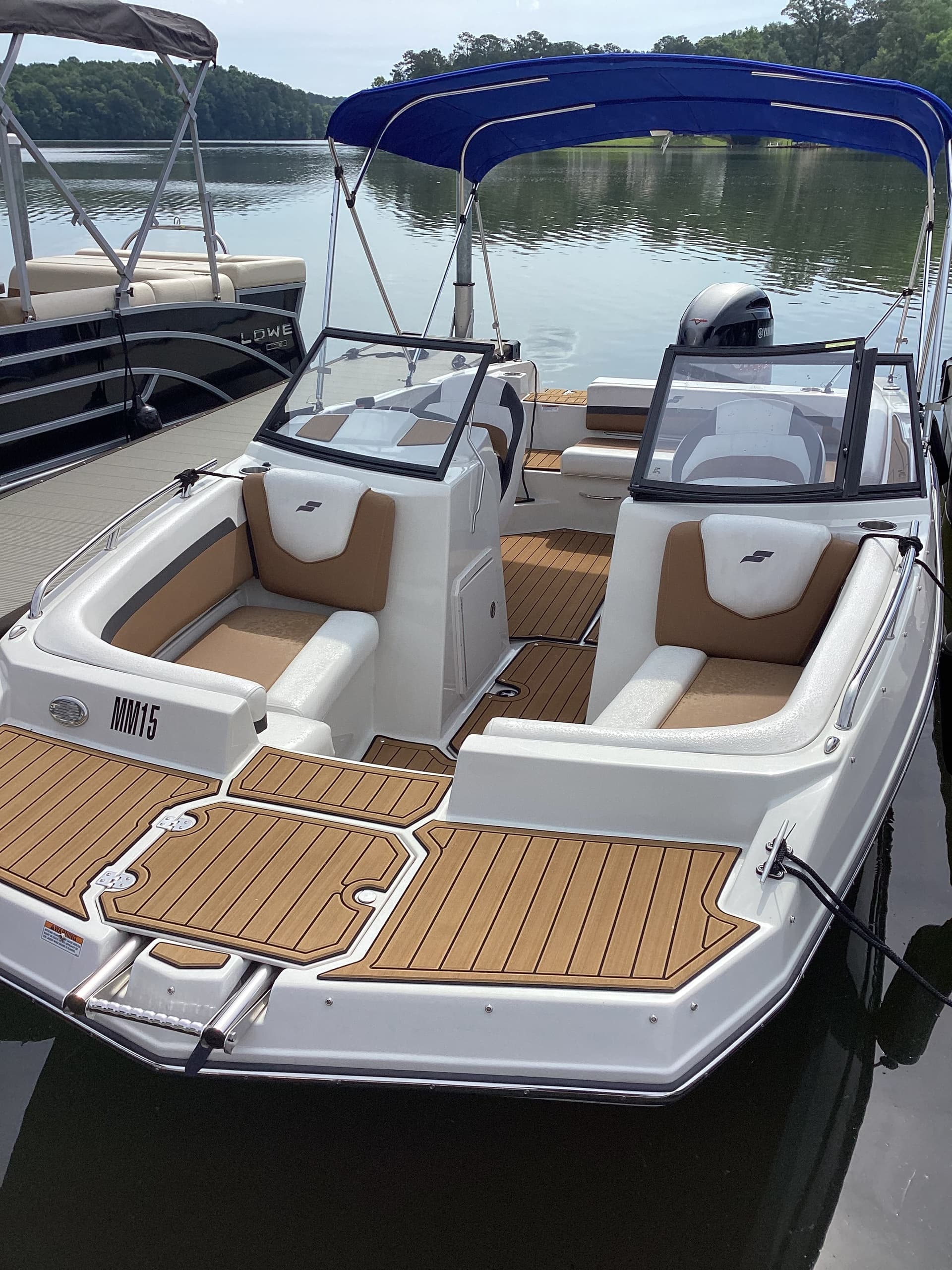 Bowrider moored on calm lake with scenic tree-lined shoreline view
