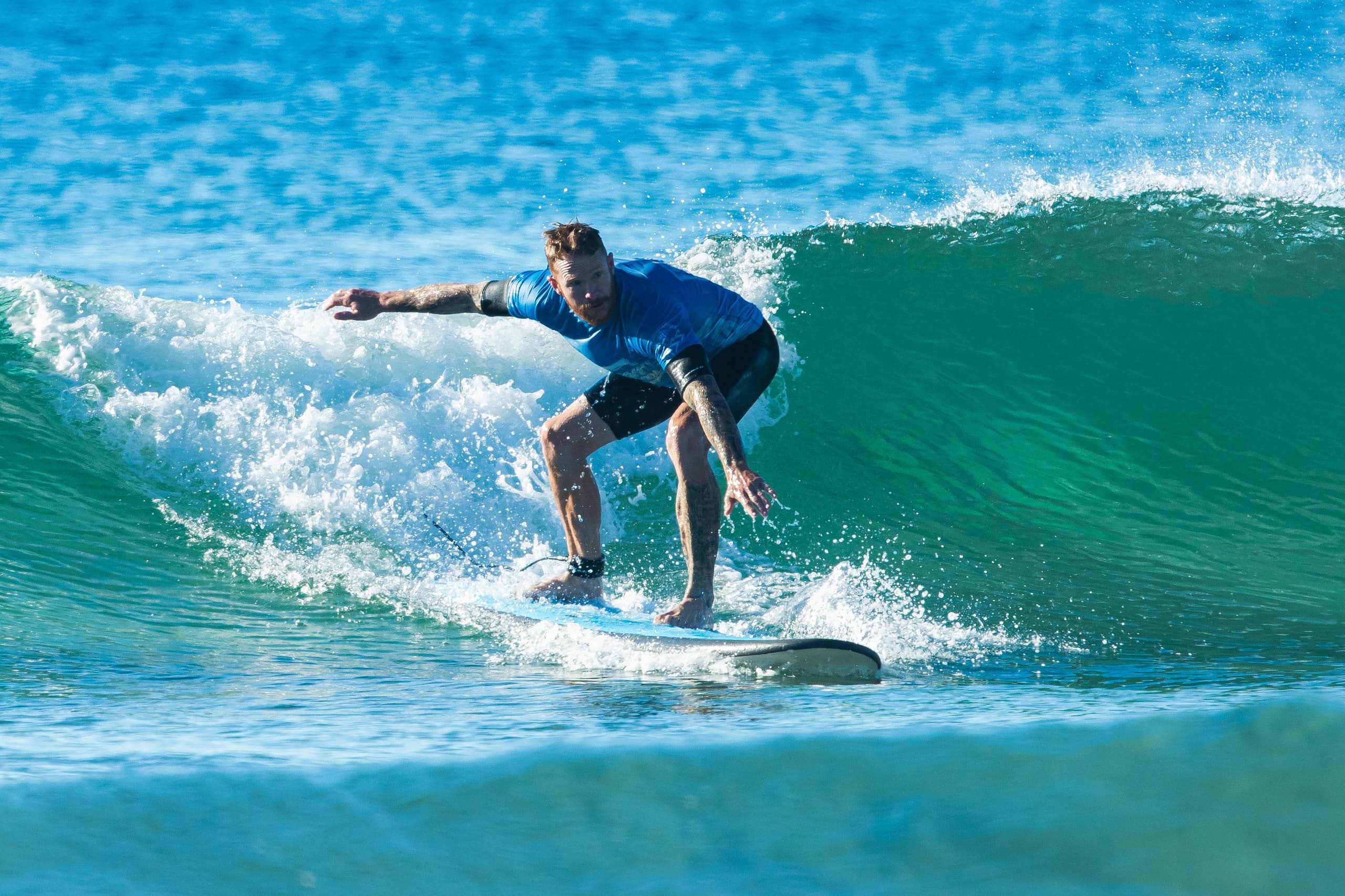 Surfer carving a clean wave crest along coastal reef with spray