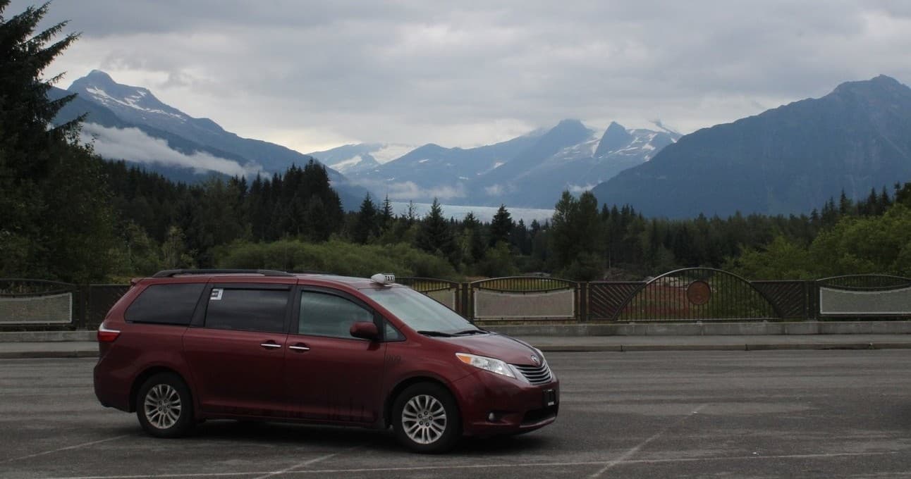 Red shuttle van parked with mountain vista, scenic roadside stop