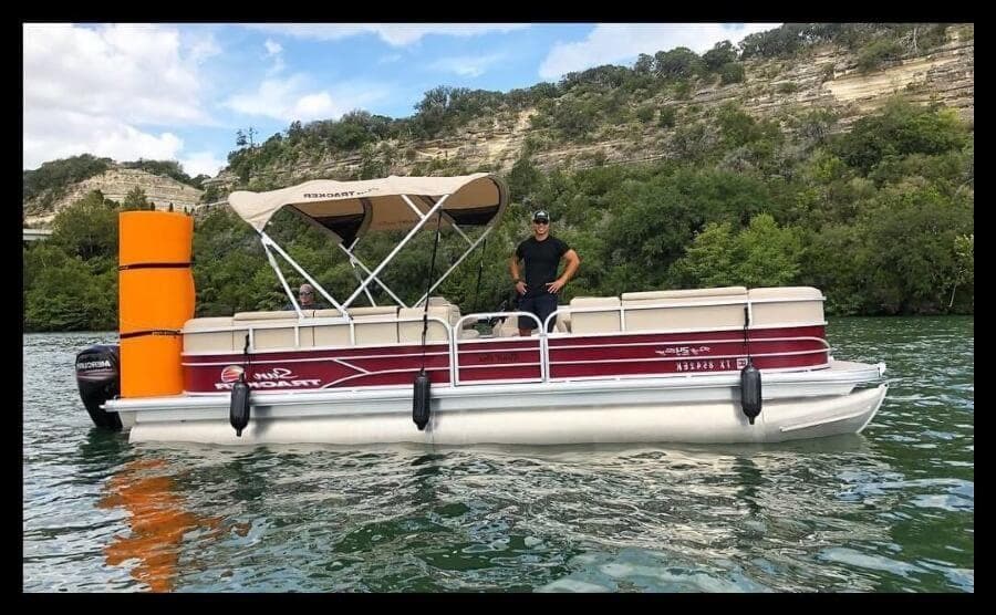 Red-striped pontoon near shoreline with buoy and operator