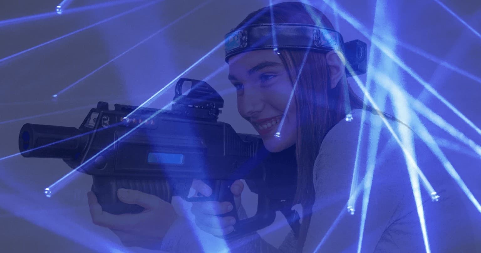 Indoor laser tag player aiming in neon lit arena beams