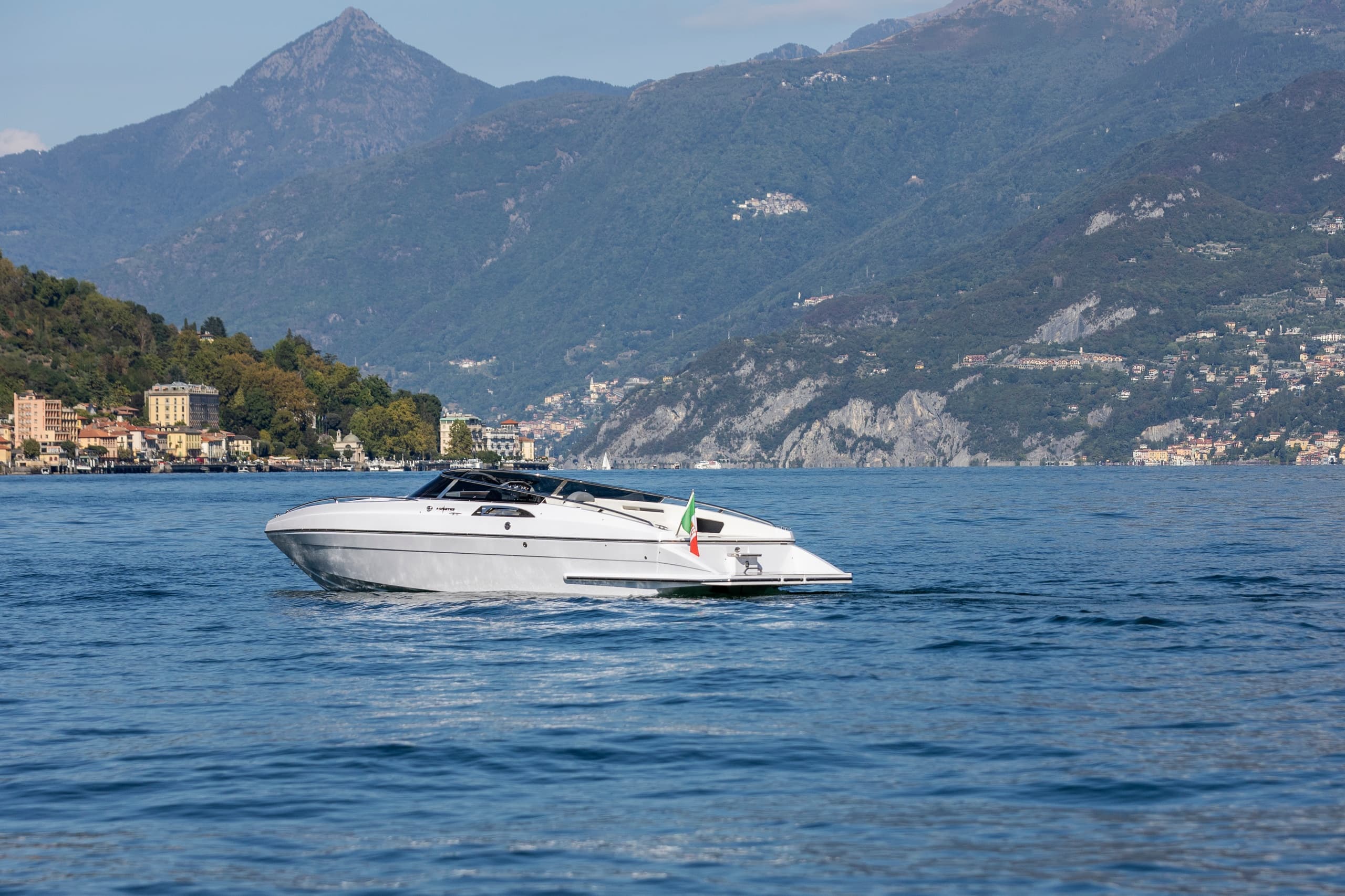 High-speed motorboat cruising on alpine lake with mountain views