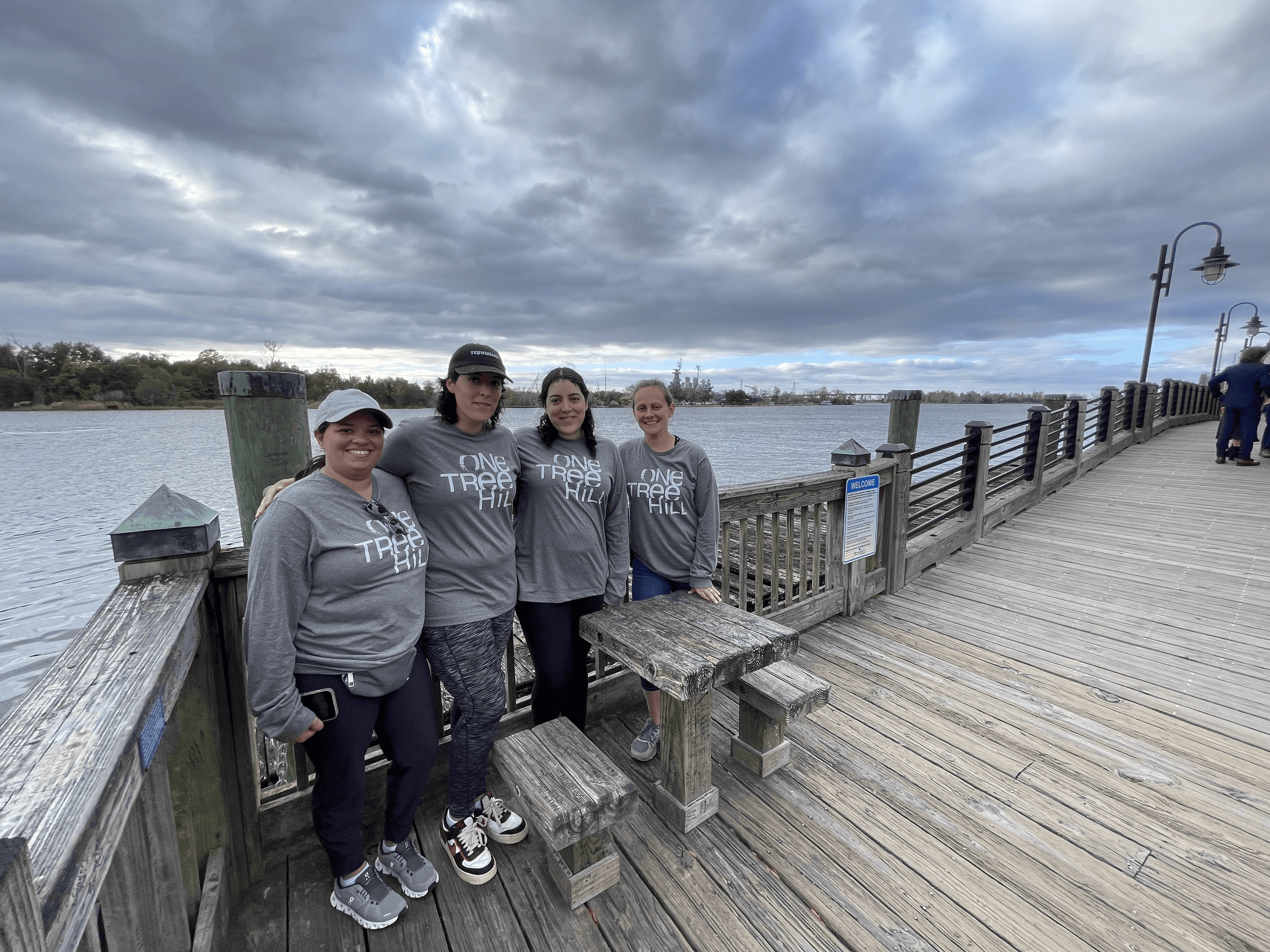 Group standing on waterfront boardwalk under dramatic clouds