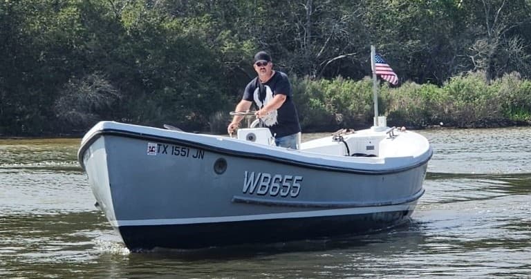 Pirogue boat cruising coastal marsh river with guide at helm
