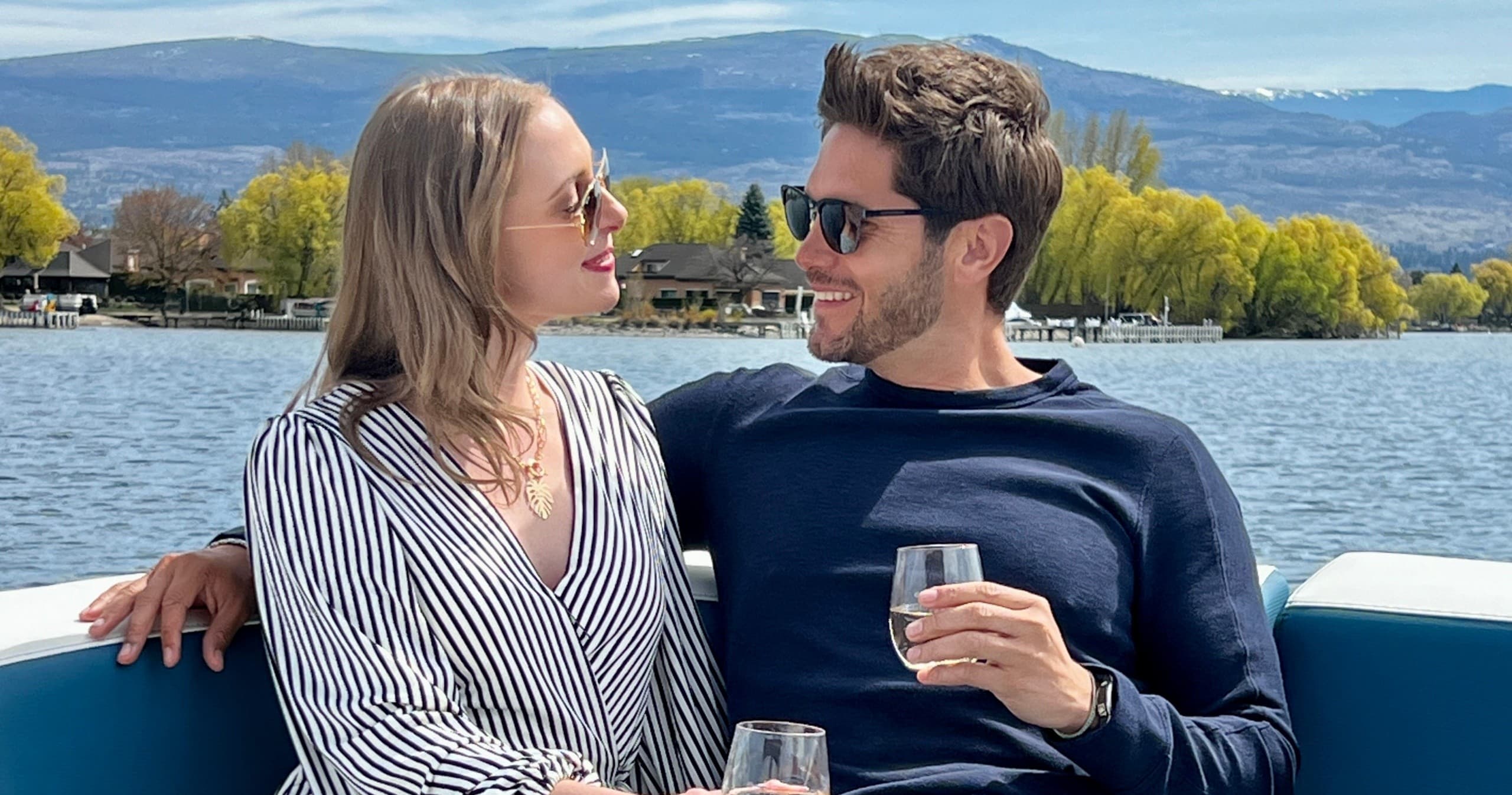 Couple relaxing on boat with wine on scenic mountain lake