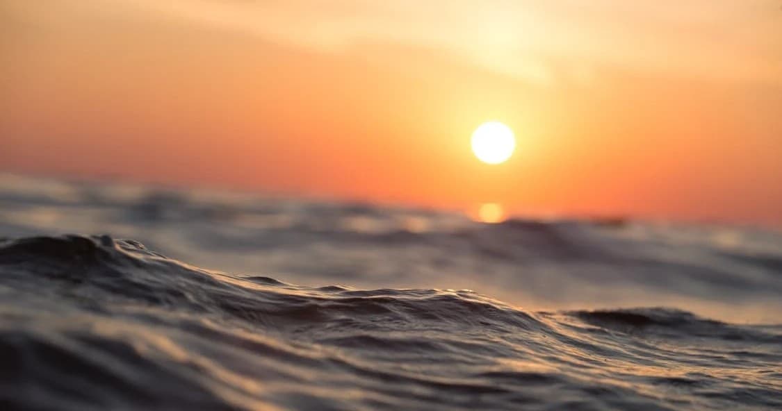 Sunset glowing over rolling ocean waves, golden surf scene
