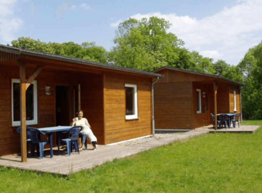 Wooden cabin bungalow on grassy lawn with outdoor seating