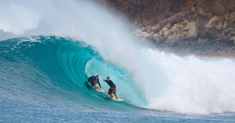 Surfer riding a blue barreling wave at a coastal reef break
