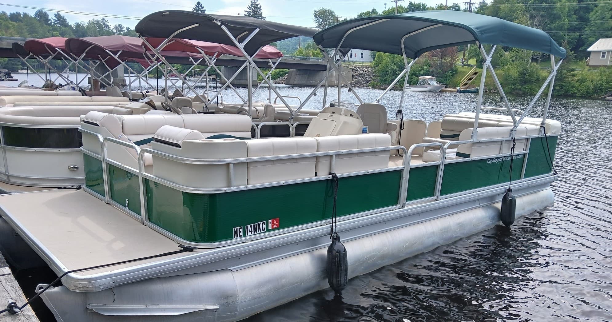 Green pontoon boat moored at dock on peaceful lake waters