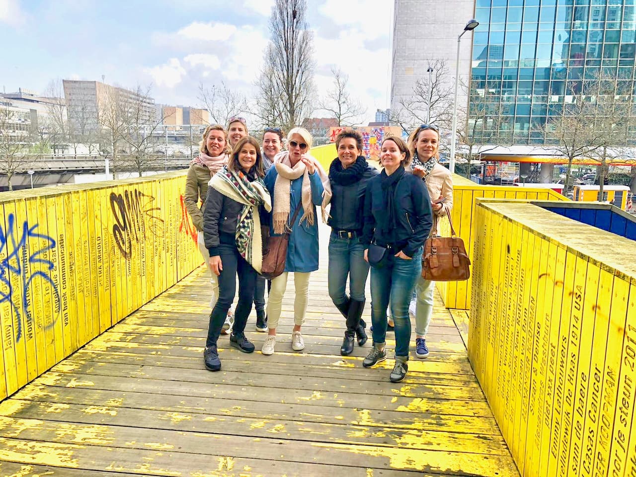Tour group walking across bright yellow pedestrian bridge outdoors