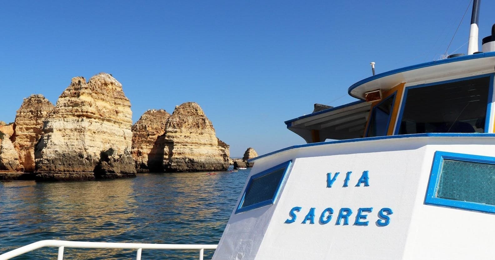 Sightseeing boat near rocky sea cliffs in Algarve, Portugal