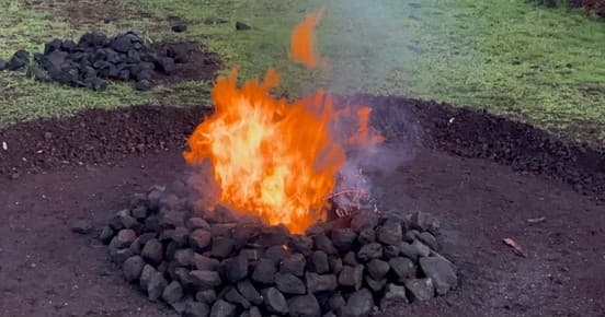Campfire blazing in stone fire pit at grassy outdoor campsite