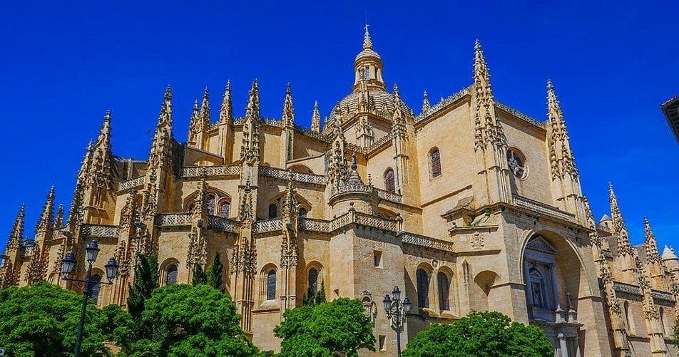 Sunlit Segovia cathedral exterior with blue sky, detailed façade