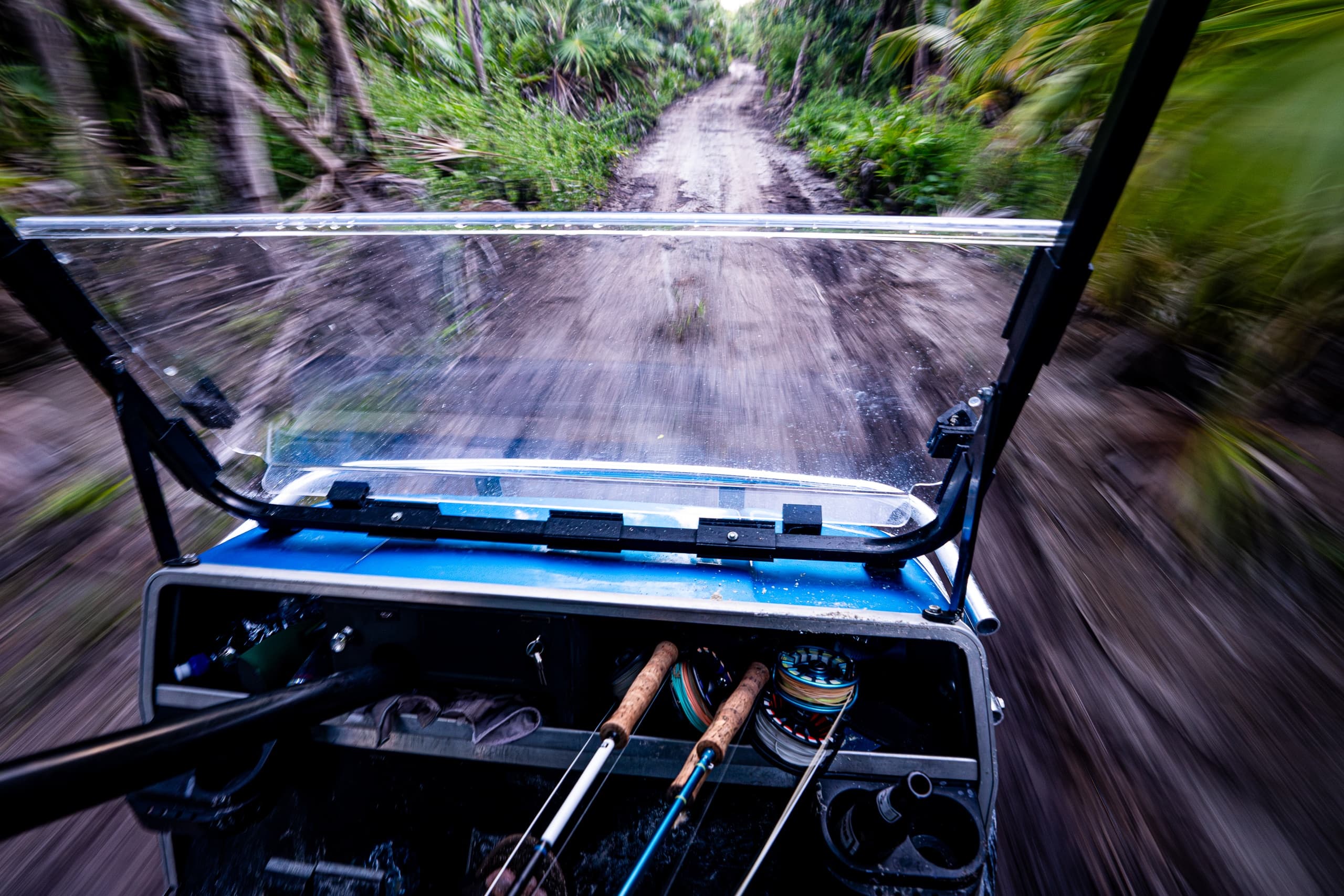 UTV dash with fly rods speeding along a wooded trail