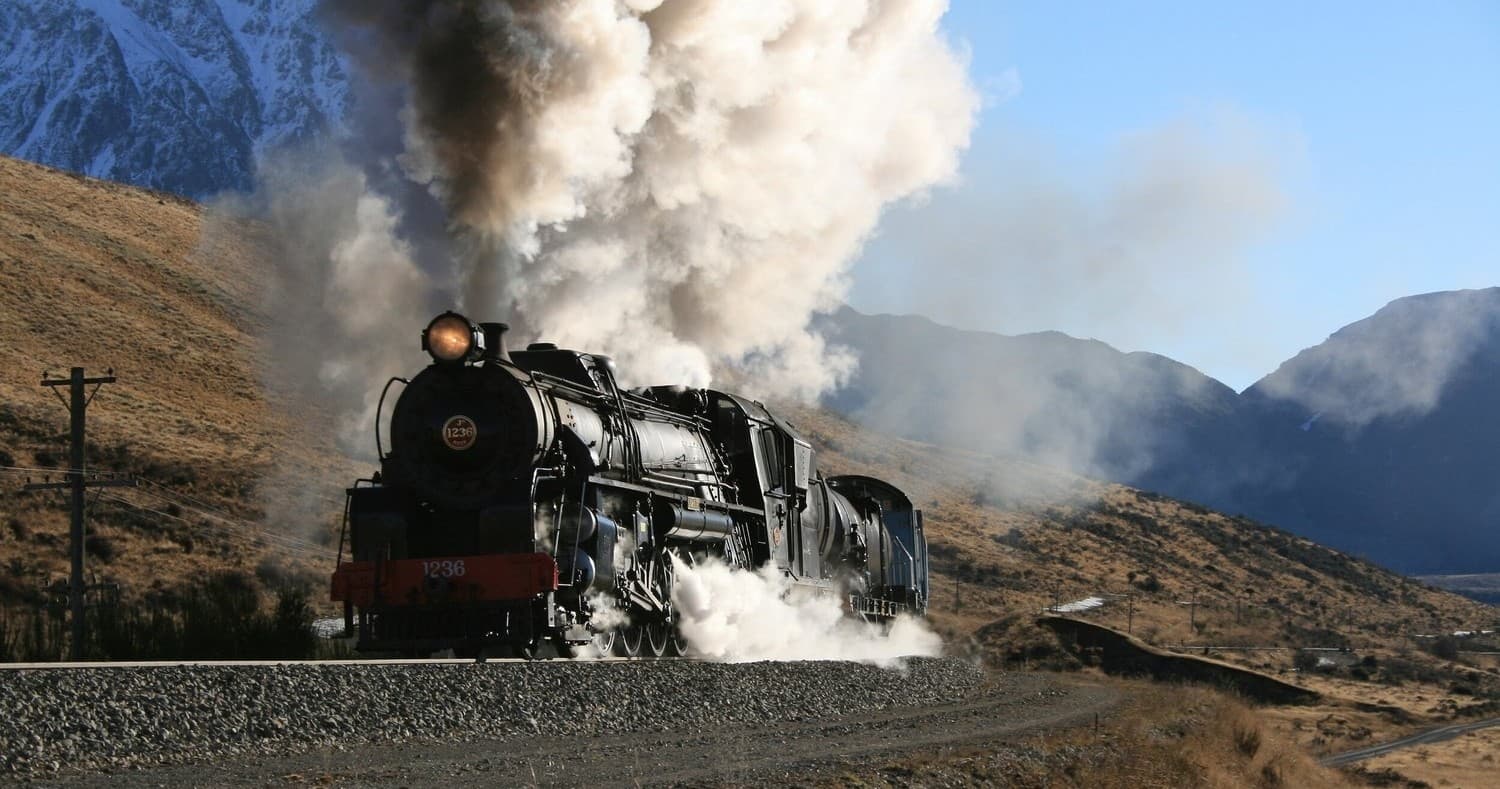 Vintage steam locomotive powering through rugged mountain pass
