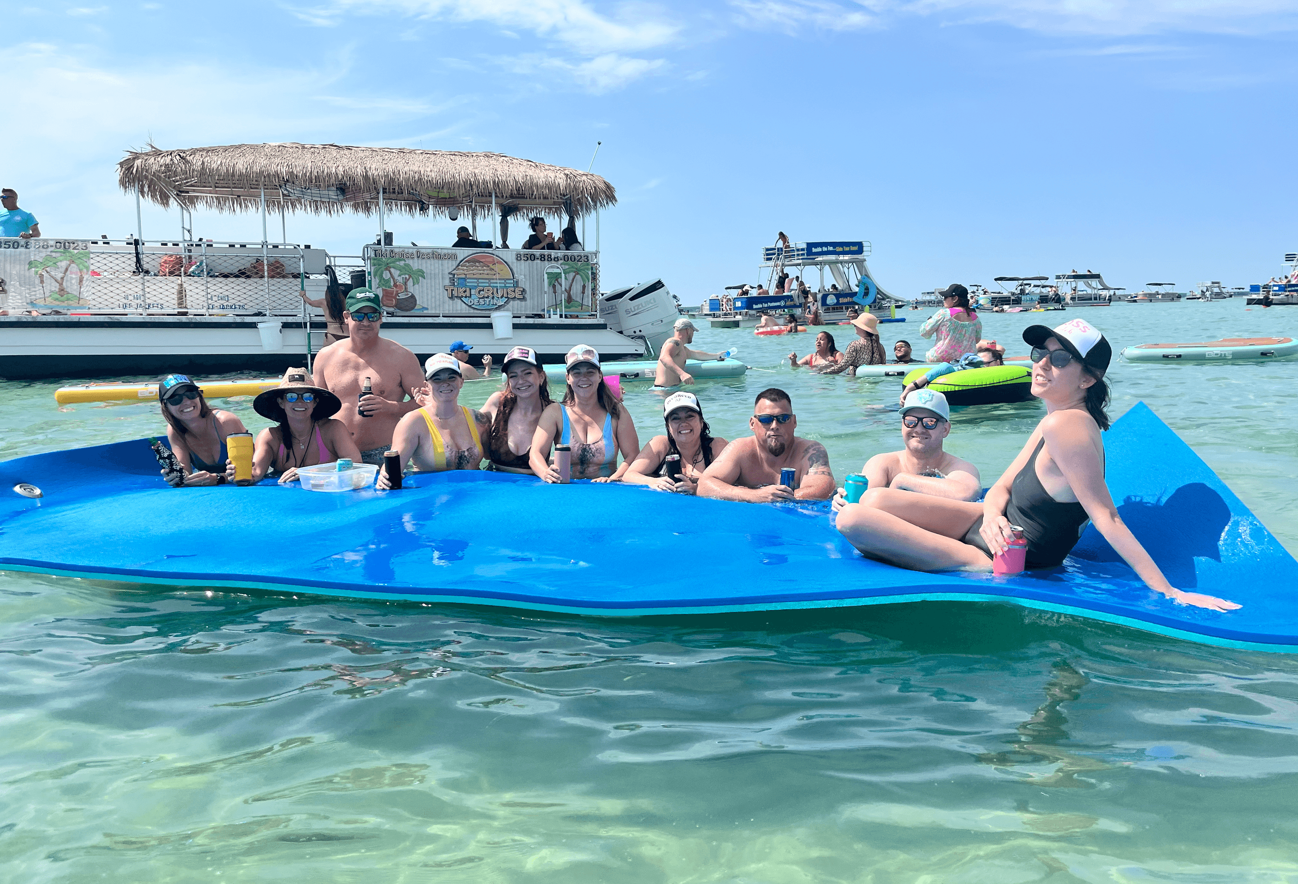 Tourists lounging on floating raft at shallow coastal sandbar