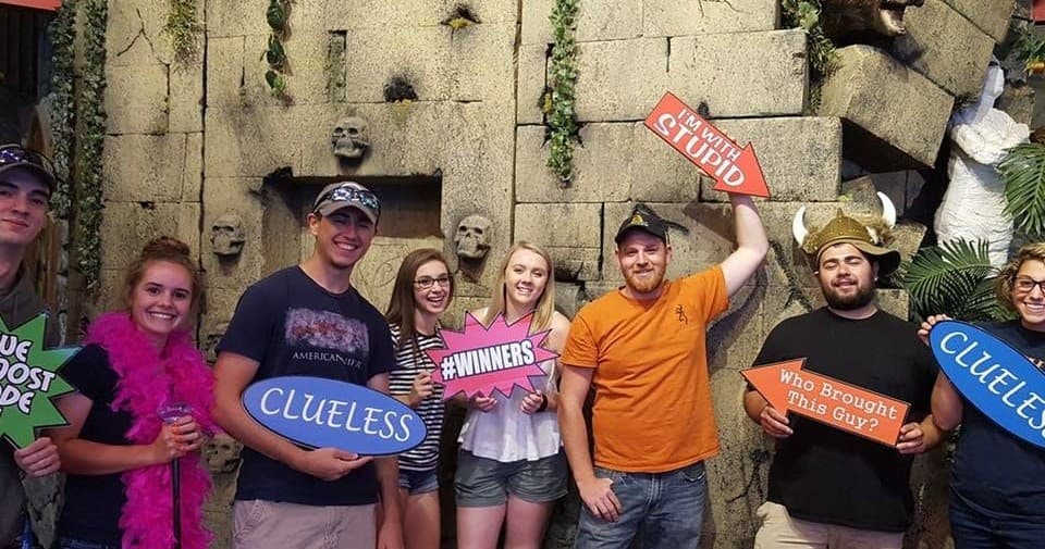 Group of escape room players posing with props in themed room