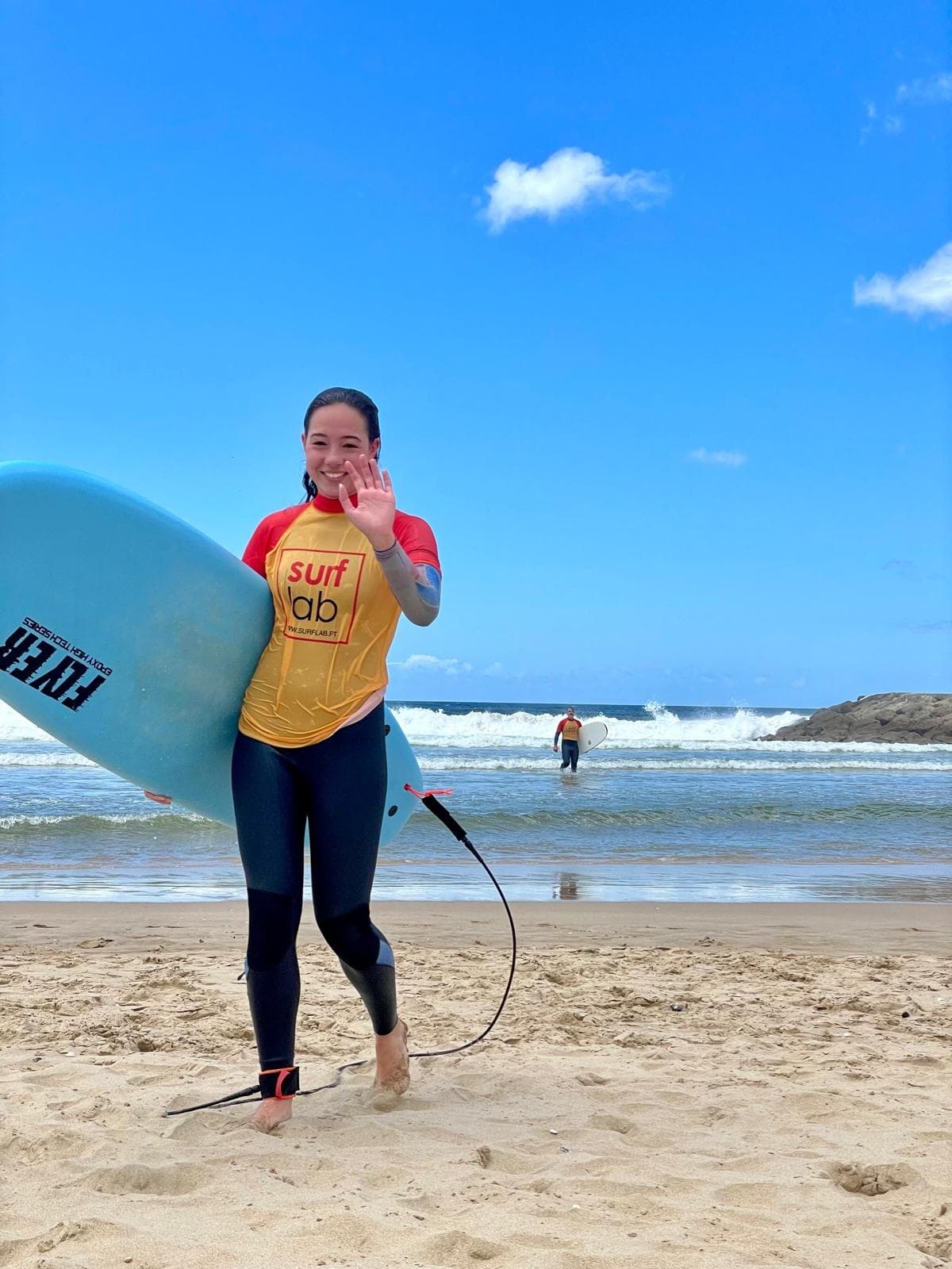 Surfer walking on sandy beach with surfboard and waves