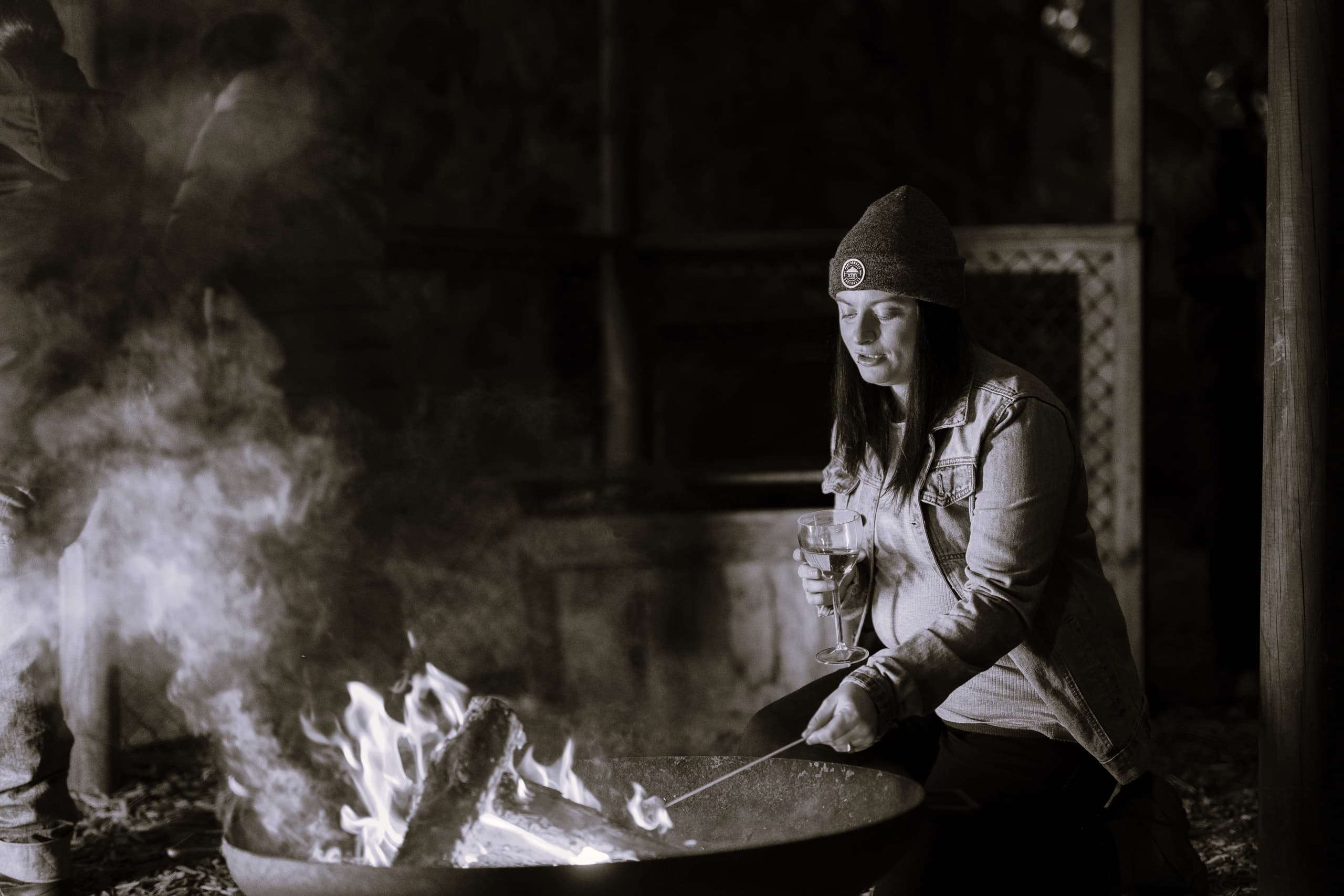 Person tending campfire at rustic outdoor shelter during night