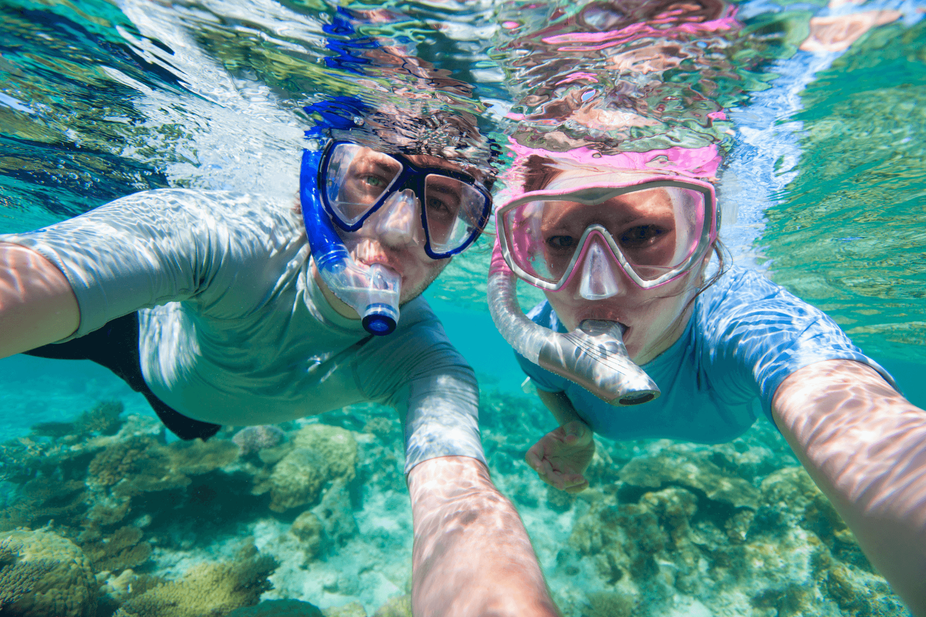 Couple snorkeling underwater over coral reef with selfie view