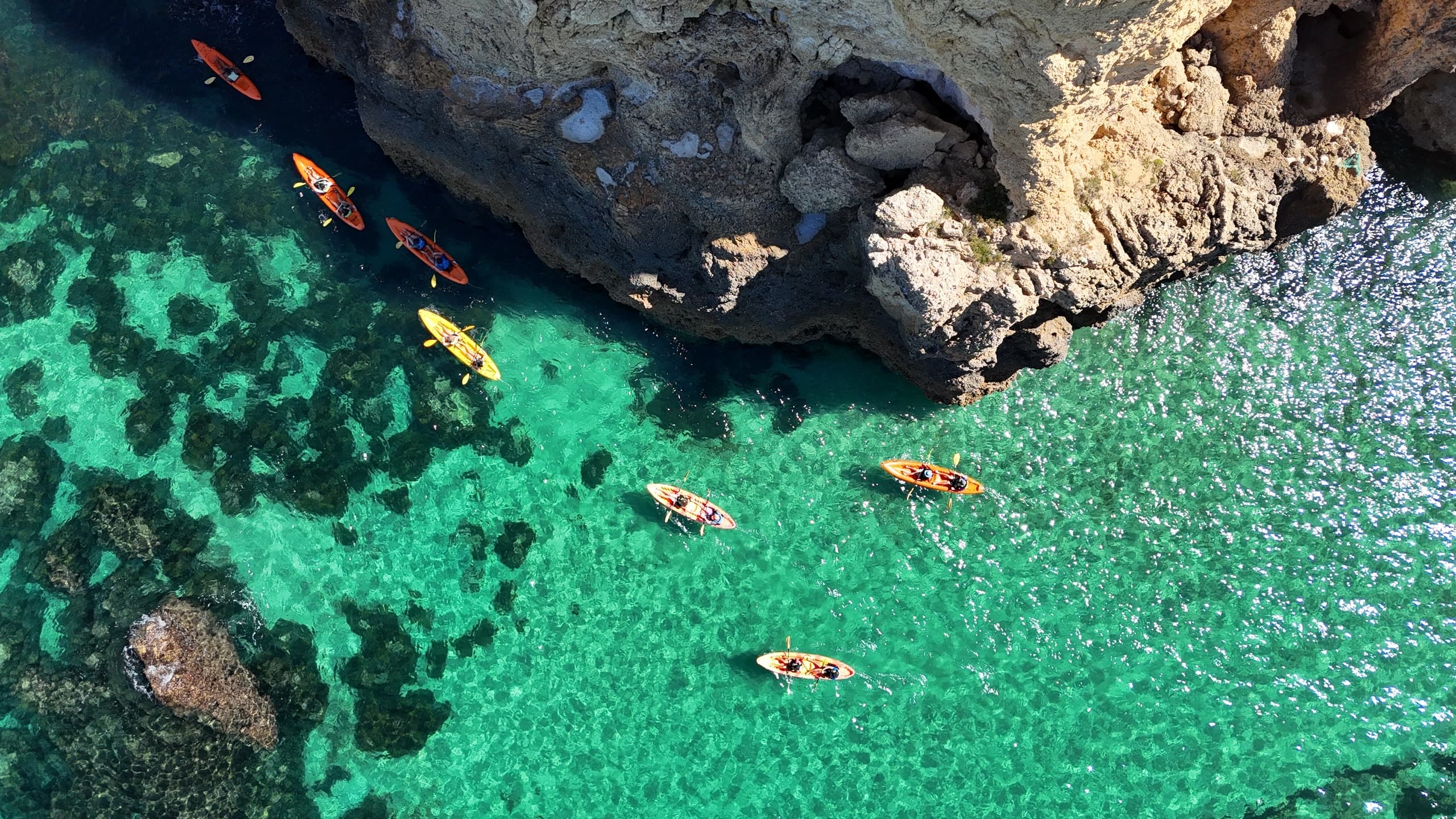 Kayakers paddling turquoise coastal waters near limestone cliffs