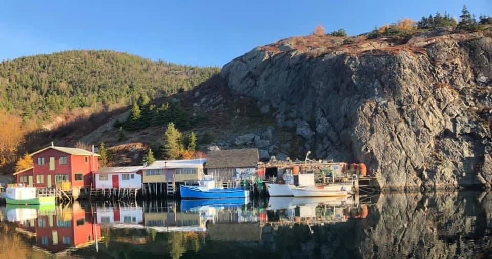 Fishing village harbor with colorful boats and rocky cliffs