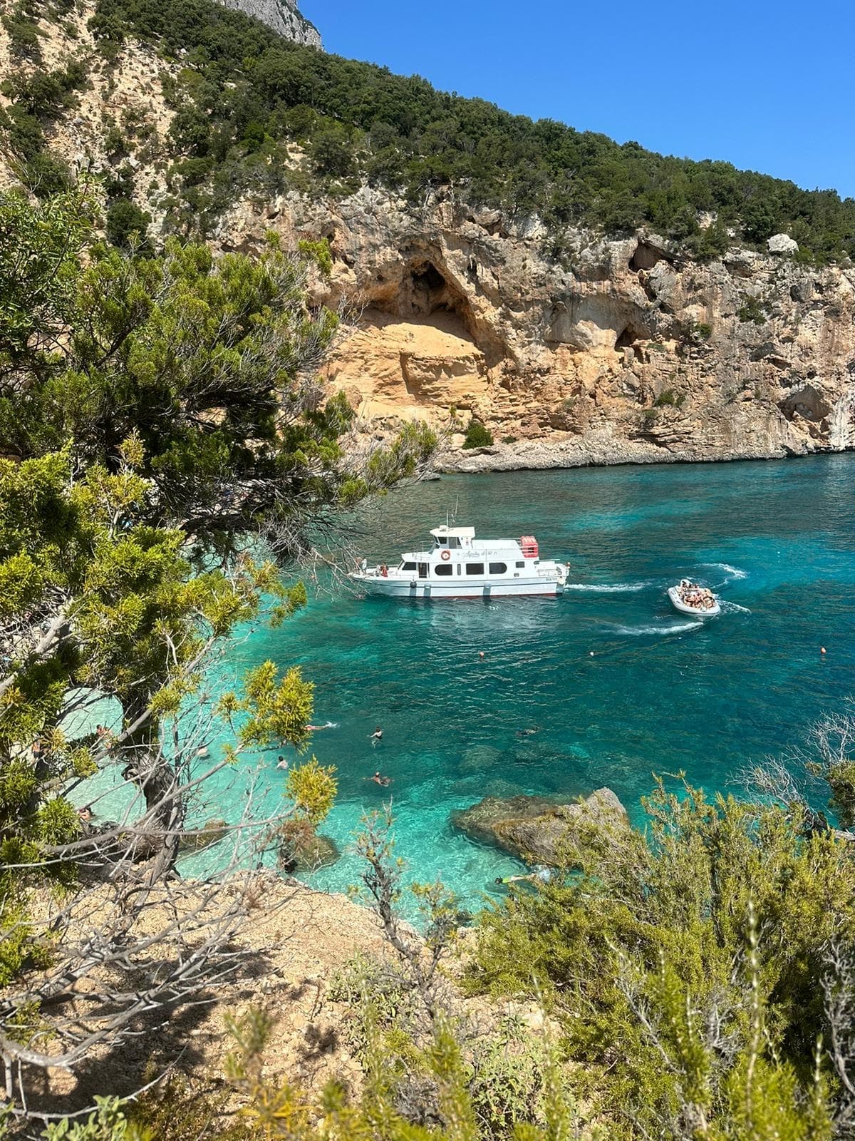 Coastal cove with anchored boat and rocky cliffs in clear water