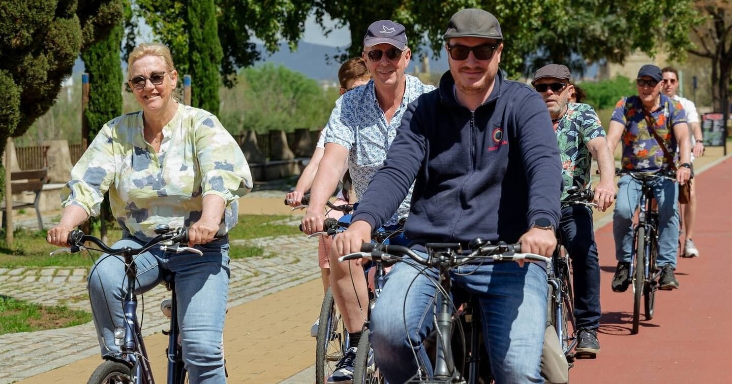 Cyclists riding scenic riverbank bike path on Córdoba tour