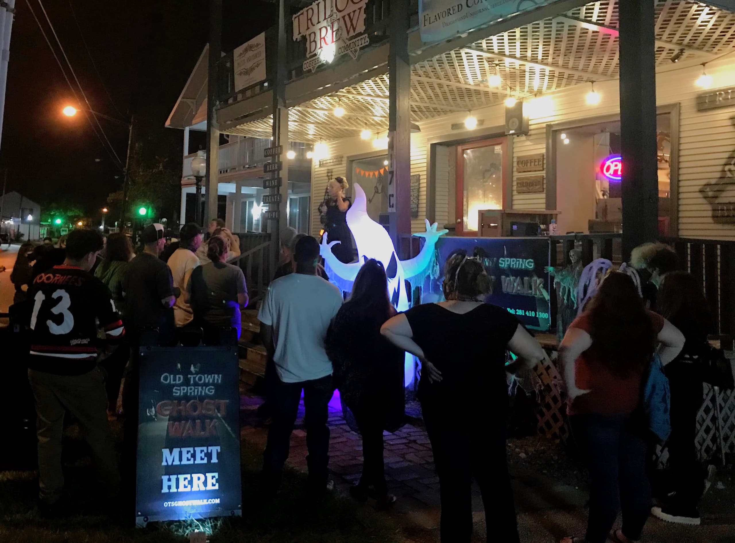 Nighttime ghost tour gathering outside old storefront in Old Town Spring