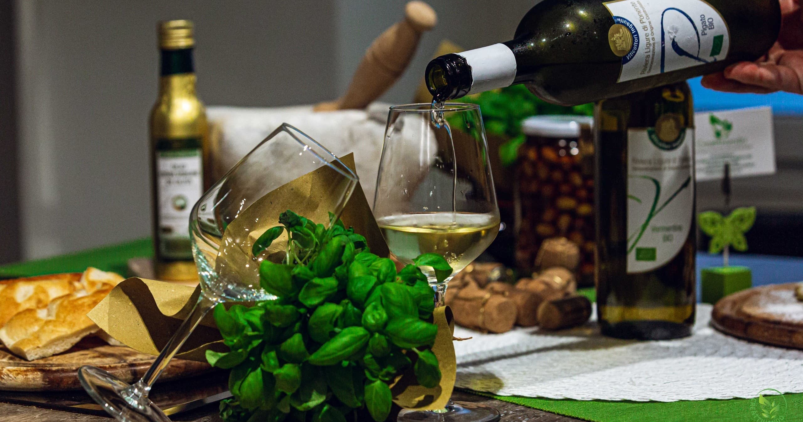 Wine poured beside fresh basil and olive oil on prep table