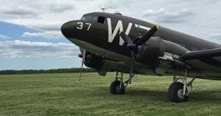 Close-up nose of restored military transport plane on grass